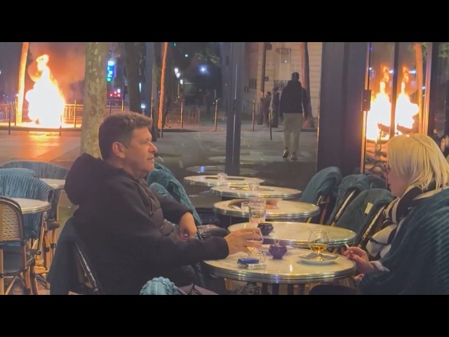 Couple Carries On Drinking, Smoking As Paris Protests Erupt Around Them