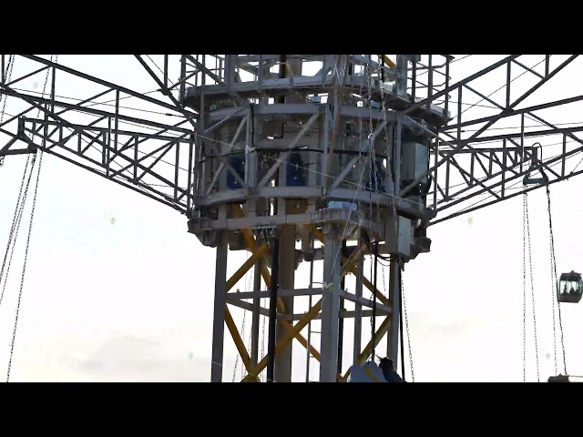 Steel amusement ride tower with radial trusses, hanging chains, and suspended cabins